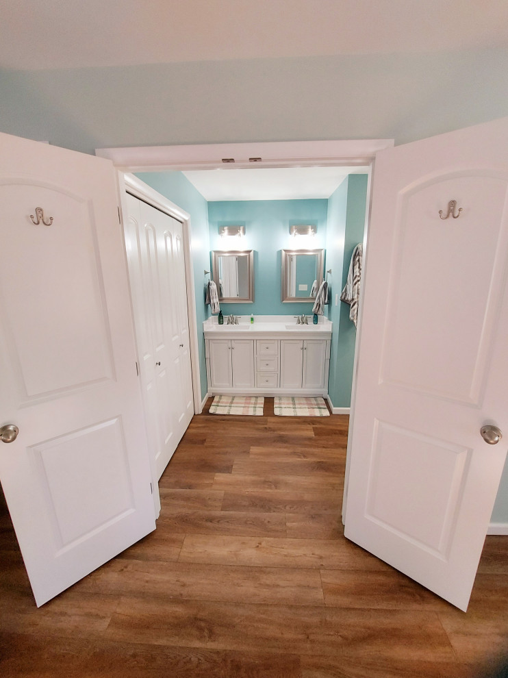 Источник вдохновения для домашнего уюта: большая главная ванная комната в стиле модернизм с белыми фасадами, душем без бортиков, унитазом-моноблоком, белой плиткой, плиткой из сланца, синими стенами, полом из ламината, накладной раковиной, столешницей из искусственного кварца, коричневым полом, душем с распашными дверями, белой столешницей, сиденьем для душа, тумбой под две раковины и встроенной тумбой