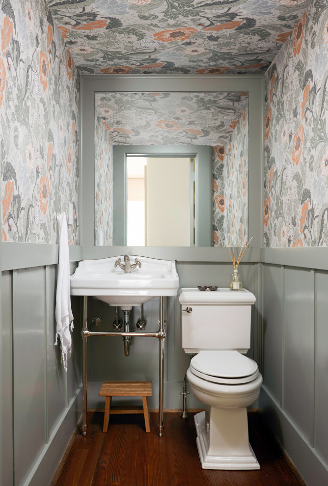 Inspiration for a small classic cloakroom in New York with white cabinets, a one-piece toilet, multi-coloured walls, medium hardwood flooring, a console sink, brown floors, a freestanding vanity unit, a wallpapered ceiling and wallpapered walls.