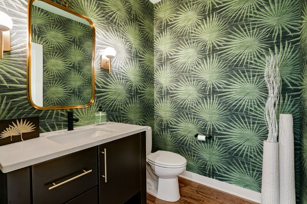 Réalisation d'un WC et toilettes vintage de taille moyenne avec un mur vert, un sol en bois brun, un lavabo encastré, un plan de toilette en granite, un sol marron, un plan de toilette blanc, meuble-lavabo encastré et du papier peint.