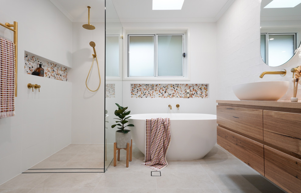 キャンベラにある中くらいな北欧スタイルのおしゃれなマスターバスルーム (中間色木目調キャビネット、置き型浴槽、オープン型シャワー、白いタイル、セラミックタイルの床、洗面台1つ、フローティング洗面台) の写真