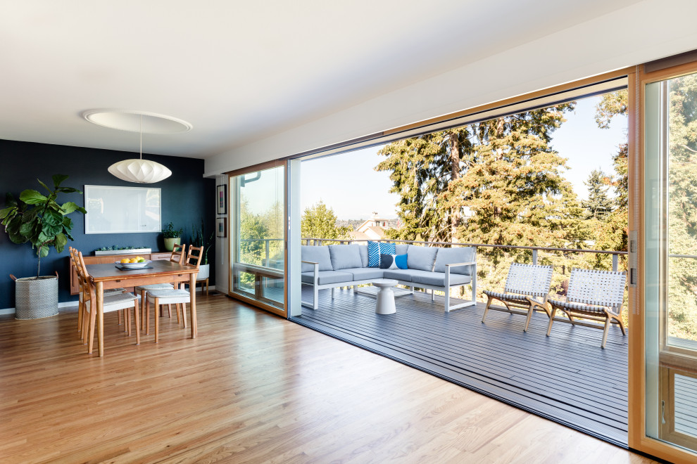Esempio di una sala da pranzo aperta verso il soggiorno minimalista di medie dimensioni con pareti nere, pavimento in legno massello medio e pavimento marrone