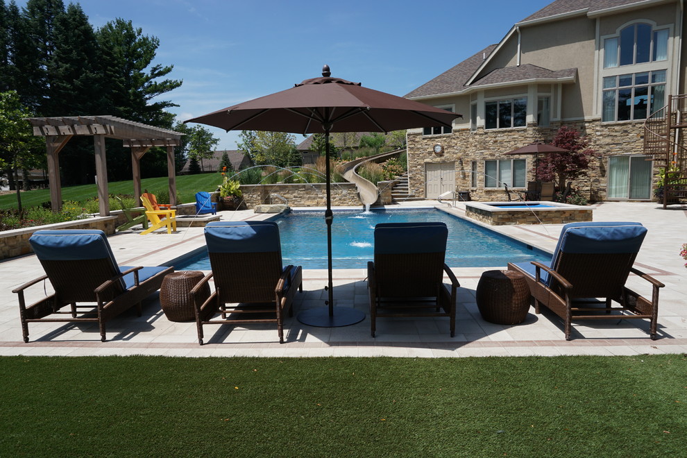 Large transitional backyard rectangular lap pool in Other with a water slide and concrete pavers.