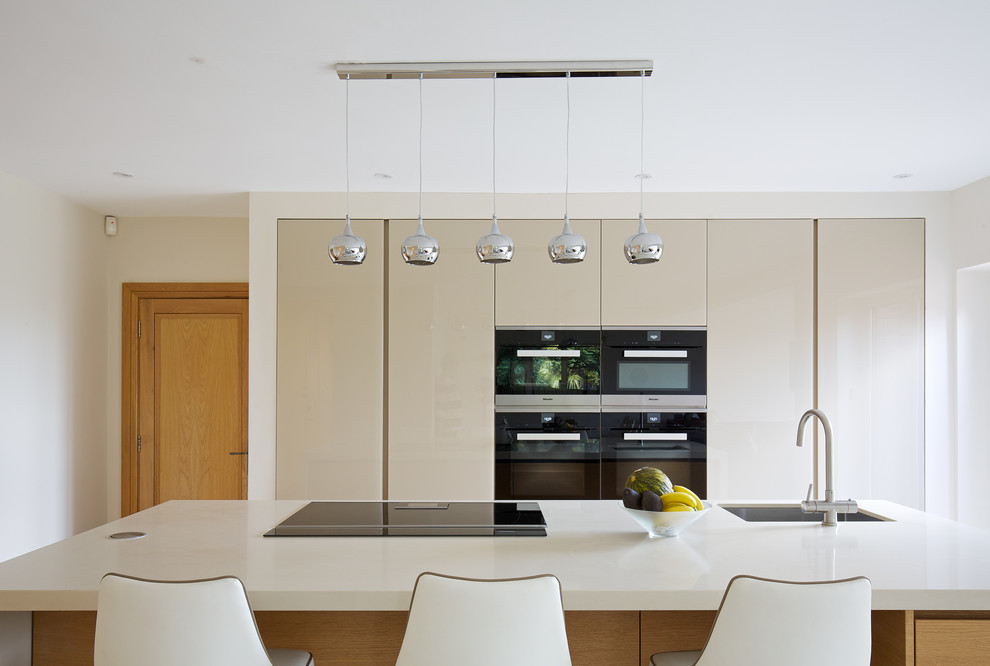 Design ideas for a large contemporary single-wall eat-in kitchen in London with an undermount sink, flat-panel cabinets, beige cabinets, solid surface benchtops, stainless steel appliances, ceramic floors, with island and white floor.