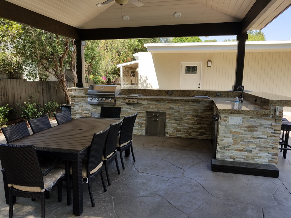 Photo of a mid-sized modern backyard patio in Los Angeles with an outdoor kitchen, a pergola and stamped concrete.