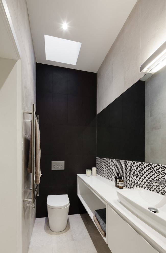 Design ideas for a small contemporary 3/4 bathroom in Sydney with a vessel sink, flat-panel cabinets, white cabinets, a wall-mount toilet, multi-coloured tile, ceramic tile, black walls and porcelain floors.
