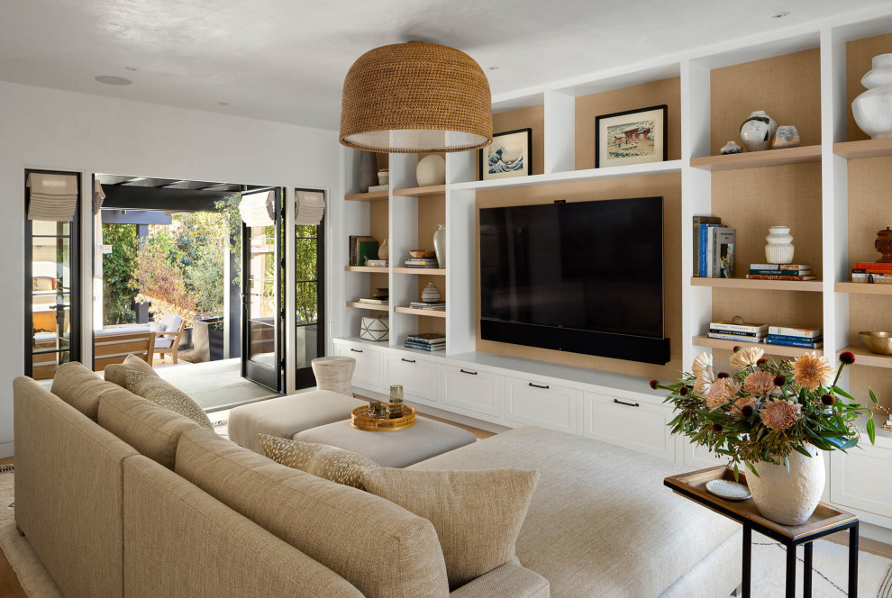 This is an example of an expansive transitional open concept family room in San Francisco with white walls, light hardwood floors, a built-in media wall and beige floor.