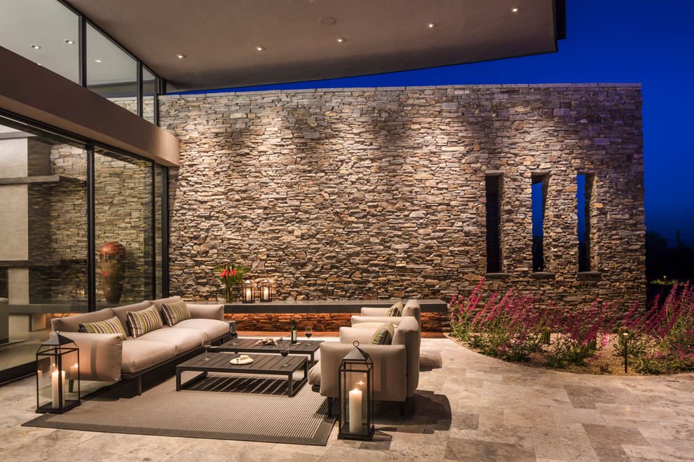 Design ideas for an expansive contemporary backyard patio in Phoenix with natural stone pavers and a roof extension.