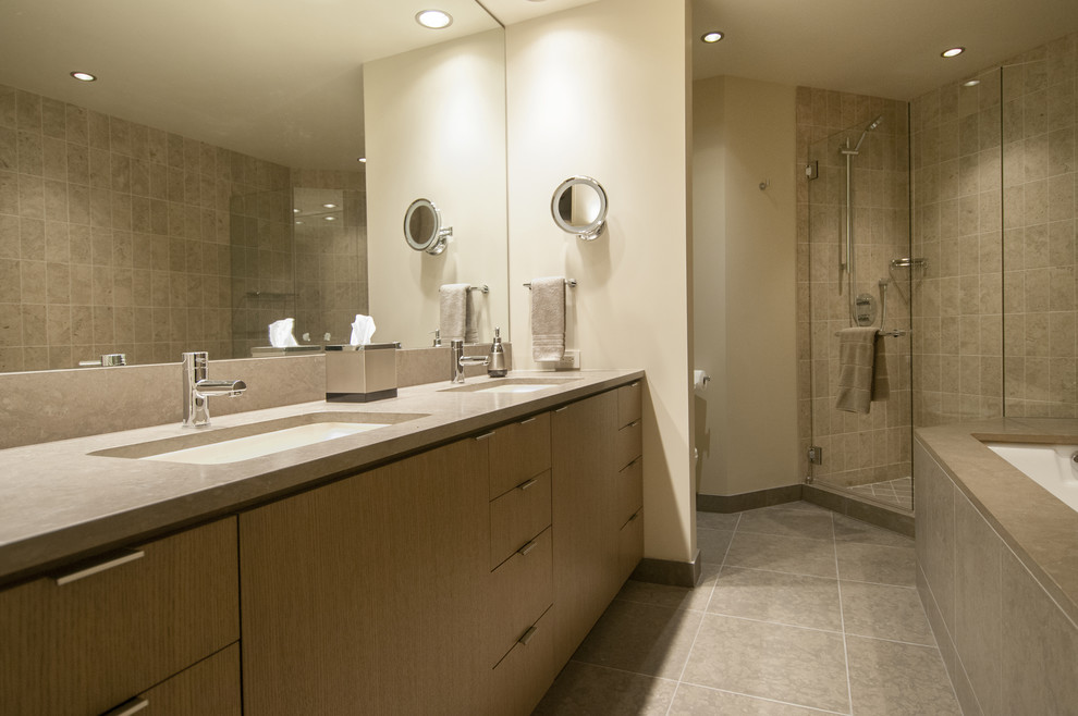 Design ideas for a large contemporary master bathroom in Seattle with an undermount sink, flat-panel cabinets, medium wood cabinets, a bidet, a drop-in tub, an alcove shower, gray tile, stone slab, white walls, limestone floors, solid surface benchtops, grey floor and a hinged shower door.