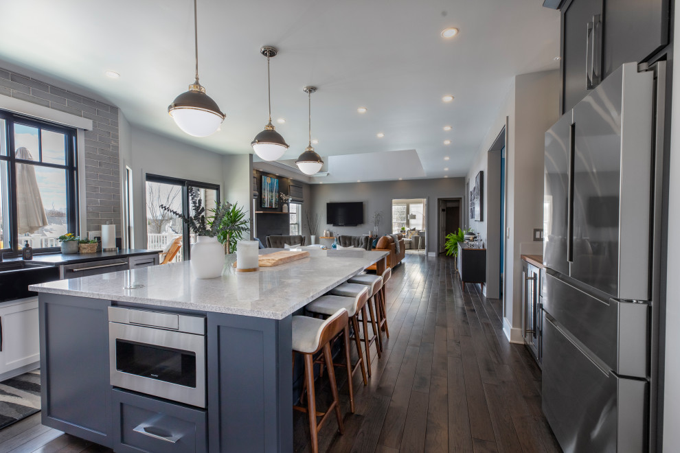 Foto di una grande cucina minimalista con lavello stile country, ante grigie, top in granito, paraspruzzi grigio, parquet scuro, pavimento marrone e top nero