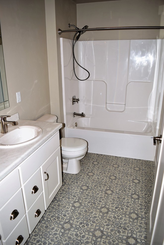 Example of a mid-sized kids' ceramic tile alcove bathtub design with recessed-panel cabinets, white cabinets, a two-piece toilet, beige walls, a drop-in sink and laminate countertops