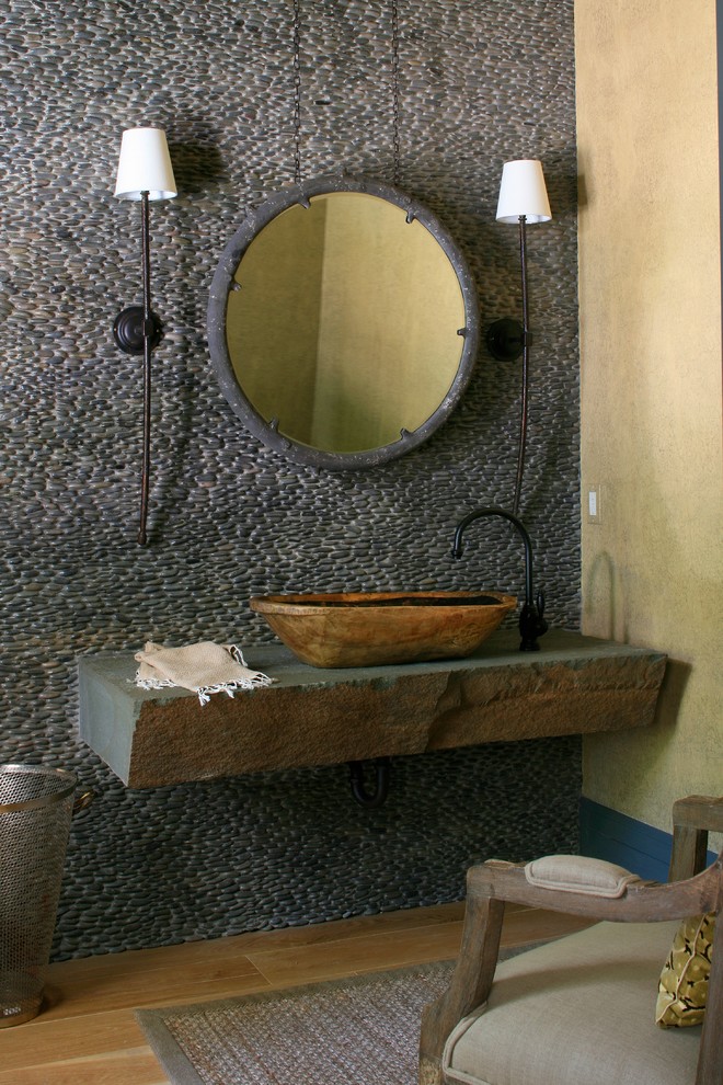 Beach style powder room in Grand Rapids with a vessel sink, concrete benchtops, light hardwood floors and pebble tile.