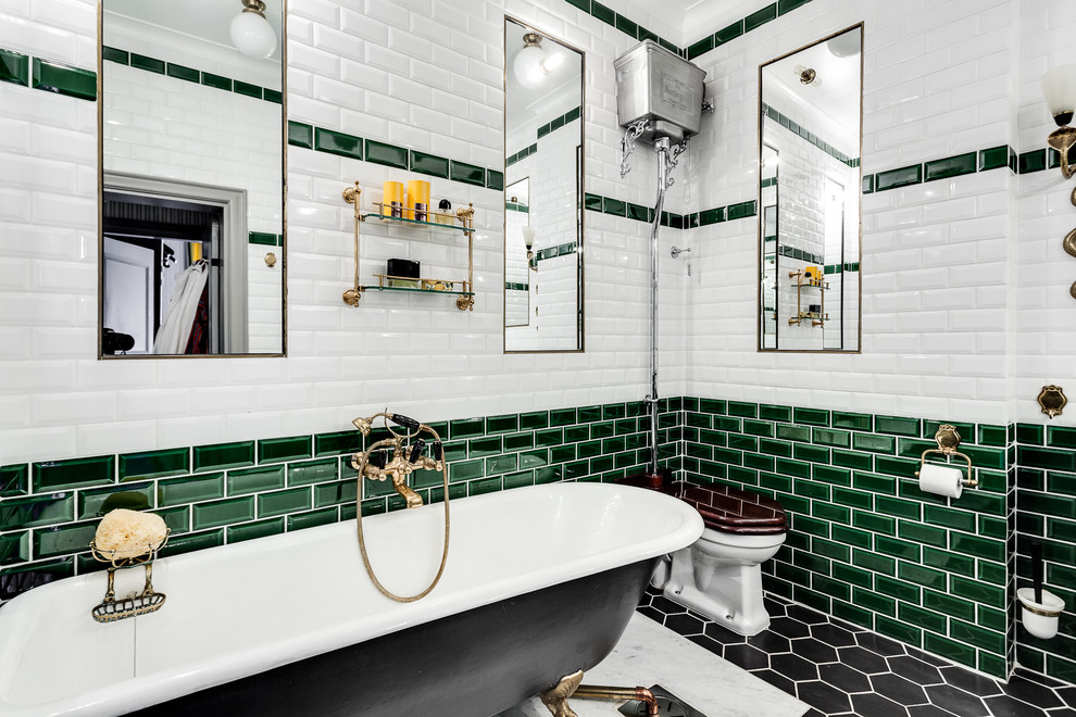 This is an example of a traditional master bathroom in Stockholm with a claw-foot tub, a one-piece toilet, black tile, green tile, white tile, subway tile and black floor.
