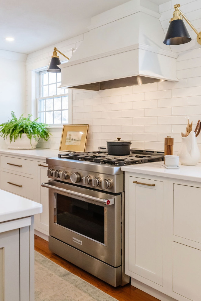 Ejemplo de cocina comedor clásica renovada con salpicadero blanco, salpicadero de azulejos tipo metro, electrodomésticos de acero inoxidable y una isla