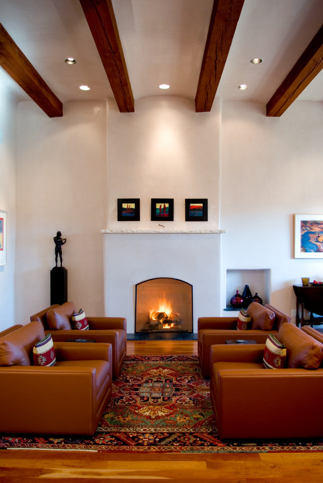 Large mediterranean formal open concept living room in Albuquerque with a standard fireplace, no tv, white walls, medium hardwood floors and a plaster fireplace surround.