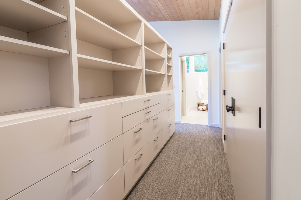 Photo of a mid-sized midcentury walk-in wardrobe in Other with flat-panel cabinets, white cabinets, carpet and grey floor.