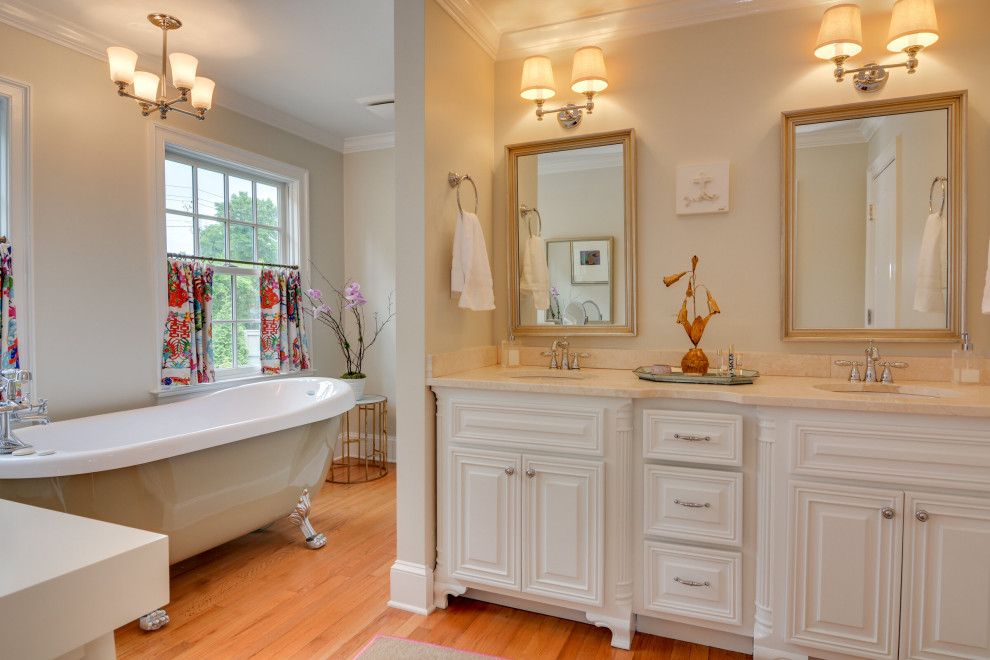Traditional bathroom in Atlanta with raised-panel cabinets, white cabinets, a claw-foot tub, beige walls, medium hardwood floors, an undermount sink, brown floor, beige benchtops and a double vanity.