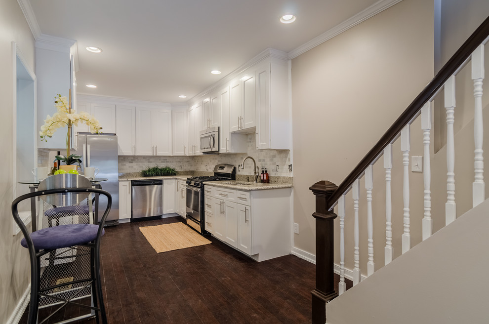 This is an example of a mid-sized transitional u-shaped eat-in kitchen in Baltimore with an undermount sink, shaker cabinets, white cabinets, granite benchtops, white splashback, marble splashback, stainless steel appliances, dark hardwood floors and no island.