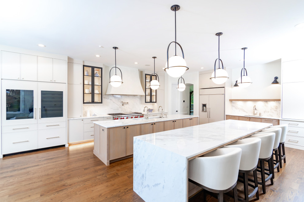This is an example of a large scandinavian eat-in kitchen in Charlotte with a drop-in sink, shaker cabinets, white cabinets, granite benchtops, multi-coloured splashback, granite splashback, stainless steel appliances, light hardwood floors, multiple islands, brown floor and white benchtop.