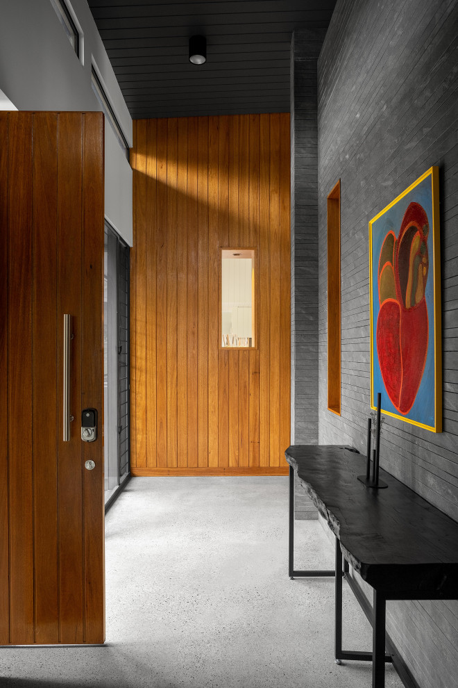 Idée de décoration pour une entrée minimaliste avec sol en béton ciré et une porte en bois brun.