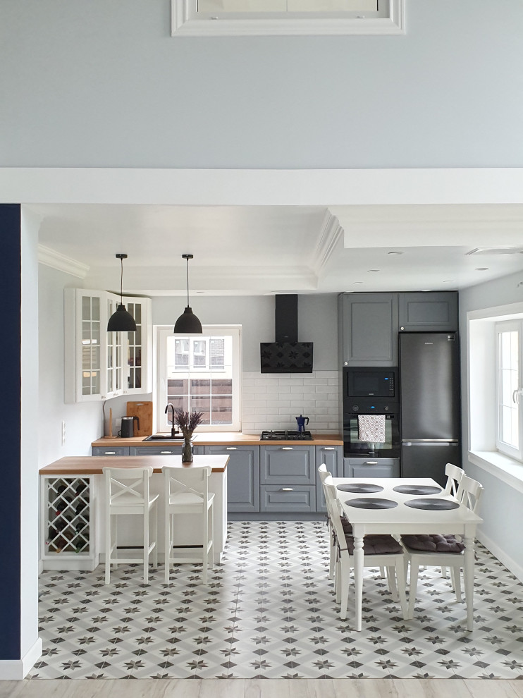 Bild på ett mellanstort vintage brun linjärt brunt kök och matrum, med luckor med upphöjd panel, grå skåp, laminatbänkskiva, vitt stänkskydd, stänkskydd i tunnelbanekakel, klinkergolv i keramik, en halv köksö och vitt golv