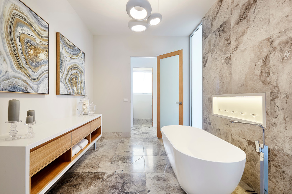 This is an example of an expansive contemporary master bathroom in Sydney with flat-panel cabinets, light wood cabinets, a freestanding tub, gray tile and white walls.