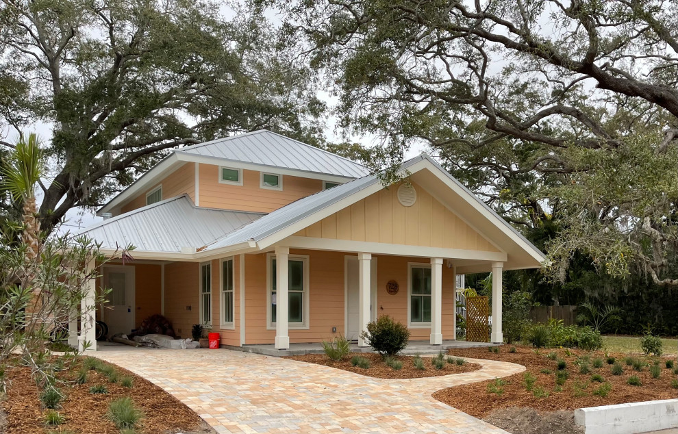 Mittelgroßes, Zweistöckiges Eklektisches Einfamilienhaus mit Vinylfassade, oranger Fassadenfarbe, Walmdach, Blechdach, grauem Dach und Verschalung in Tampa