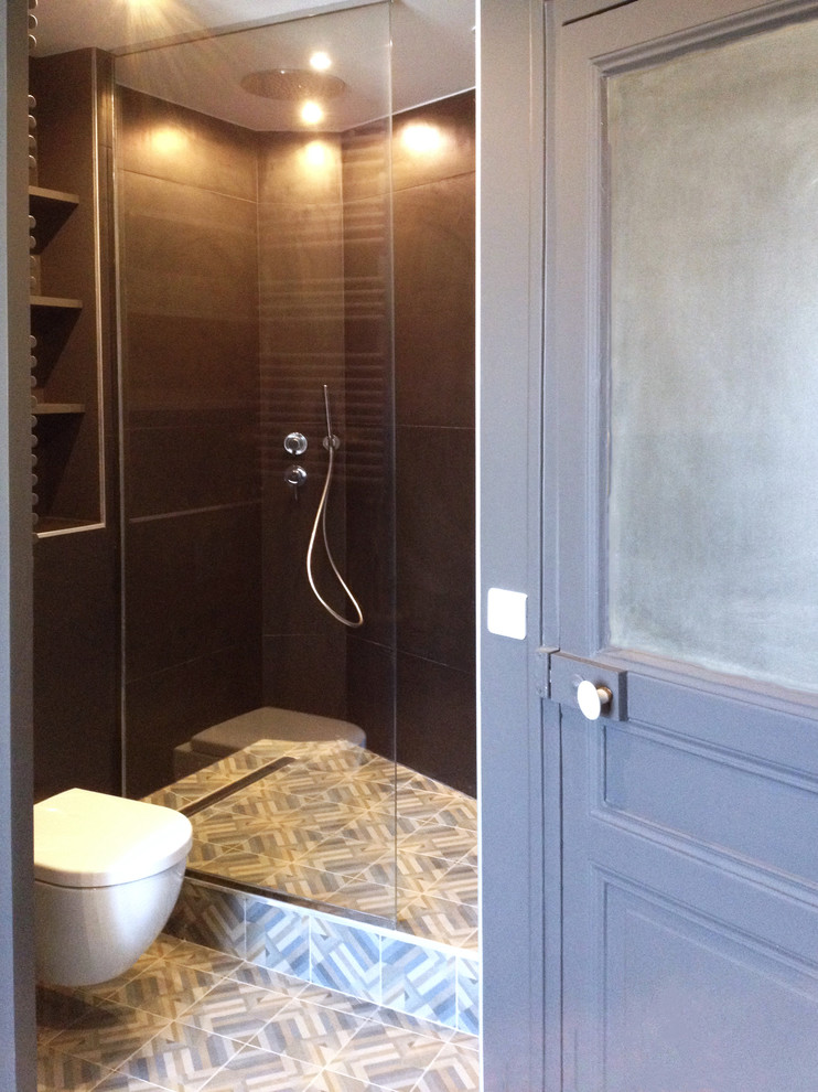 Inspiration for a mid-sized contemporary master bathroom in Paris with an undermount tub, a curbless shower, a wall-mount toilet, cement tile, black walls, ceramic floors, a wall-mount sink, glass-front cabinets, black cabinets and gray tile.