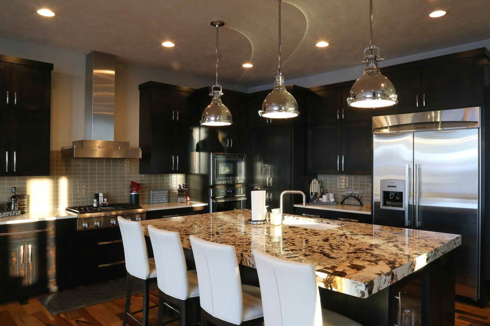 Inspiration for a large transitional l-shaped medium tone wood floor and brown floor eat-in kitchen remodel with an undermount sink, shaker cabinets, black cabinets, granite countertops, beige backsplash, porcelain backsplash, stainless steel appliances, an island and multicolored countertops