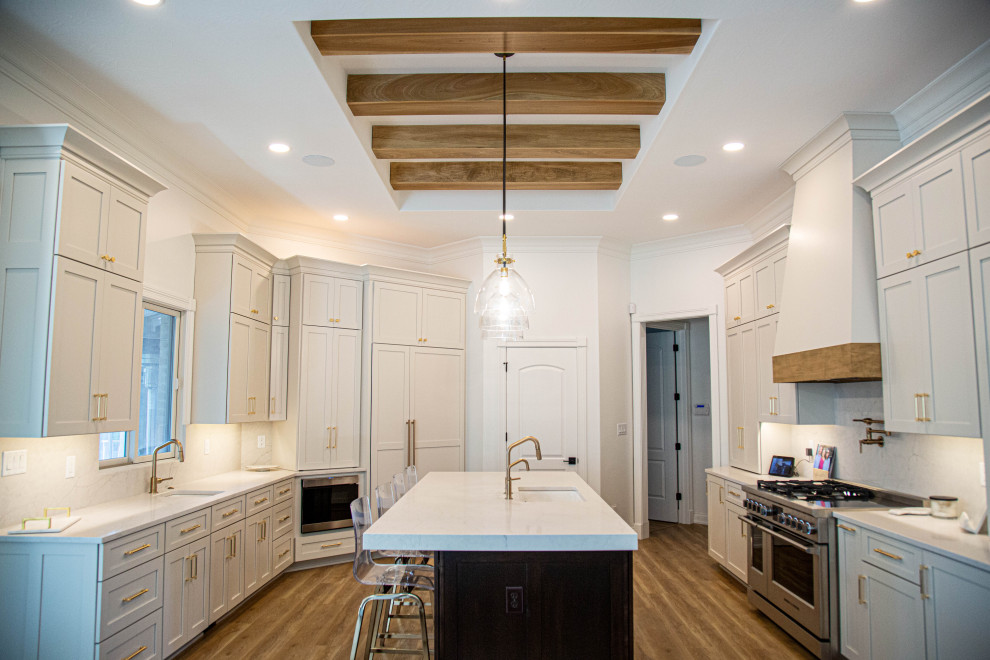Inspiration for a large transitional u-shaped eat-in kitchen in Indianapolis with an undermount sink, shaker cabinets, white cabinets, quartz benchtops, white splashback, engineered quartz splashback, stainless steel appliances, laminate floors, with island, blue floor, white benchtop and exposed beam.