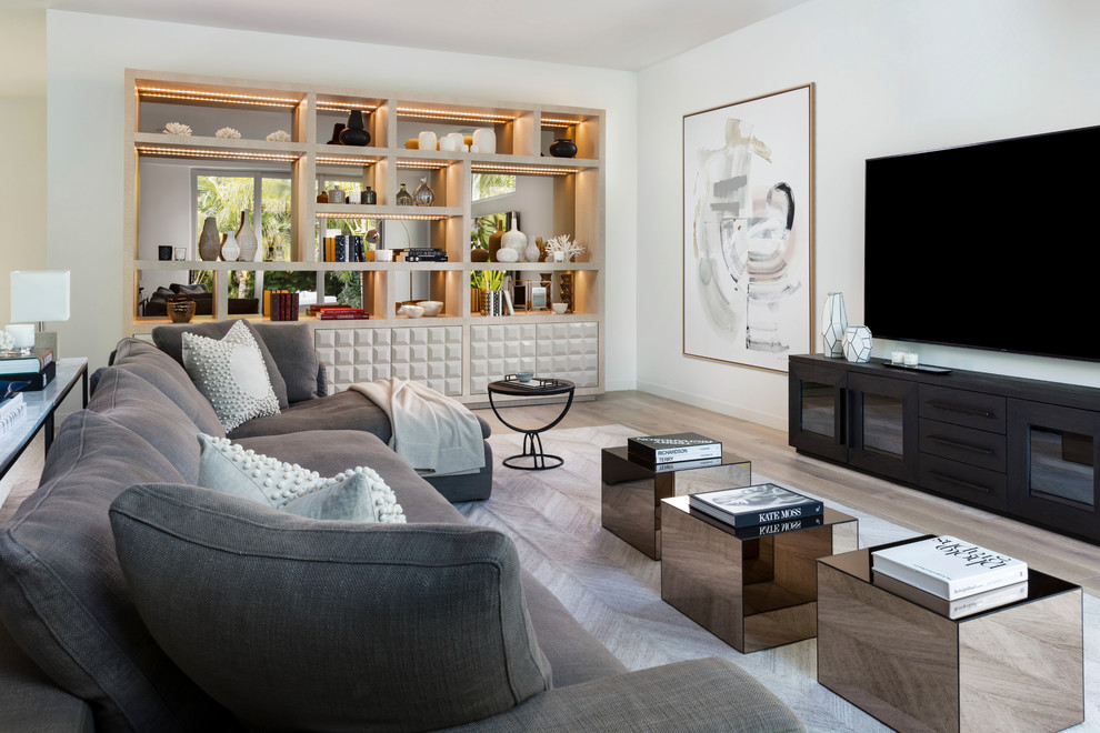 This is an example of a contemporary living room in Miami with white walls, light hardwood floors, a wall-mounted tv and beige floor.