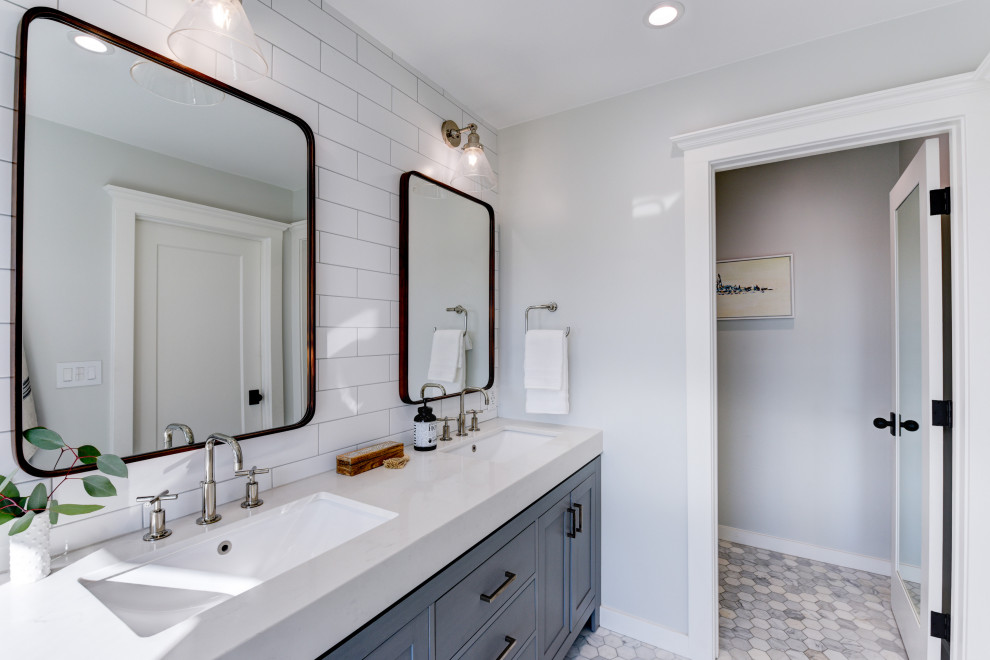This is an example of a mid-sized contemporary master bathroom in San Francisco with shaker cabinets, grey cabinets, a curbless shower, a one-piece toilet, white tile, ceramic tile, white walls, marble floors, an undermount sink, white floor, a hinged shower door, a niche, a double vanity and a freestanding vanity.