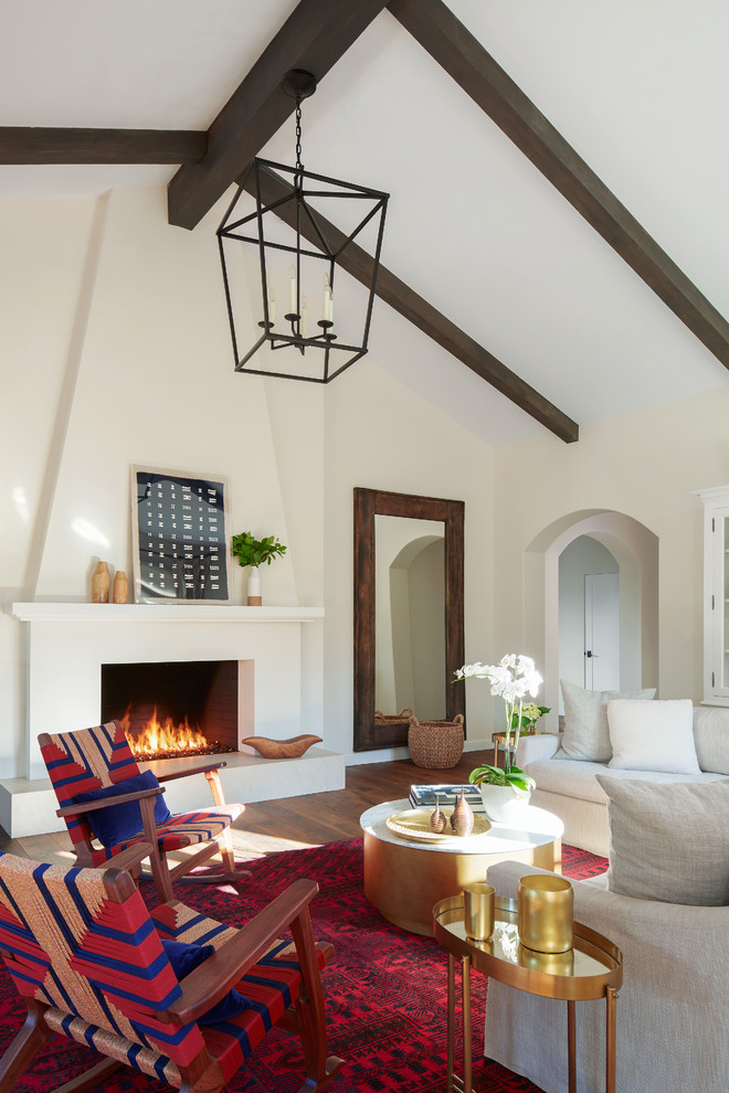Inspiration for a mediterranean living room in San Francisco with dark hardwood floors, a plaster fireplace surround, beige walls, a standard fireplace and brown floor.