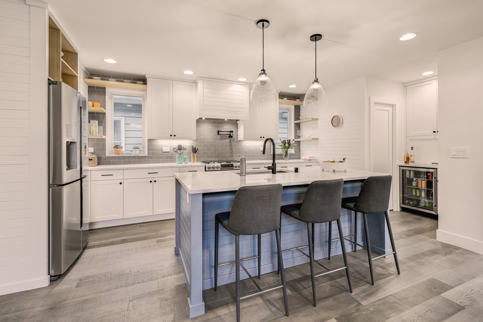 Inspiration for a small contemporary l-shaped open plan kitchen in Seattle with an undermount sink, shaker cabinets, white cabinets, quartz benchtops, grey splashback, ceramic splashback, stainless steel appliances, medium hardwood floors, with island and white benchtop.