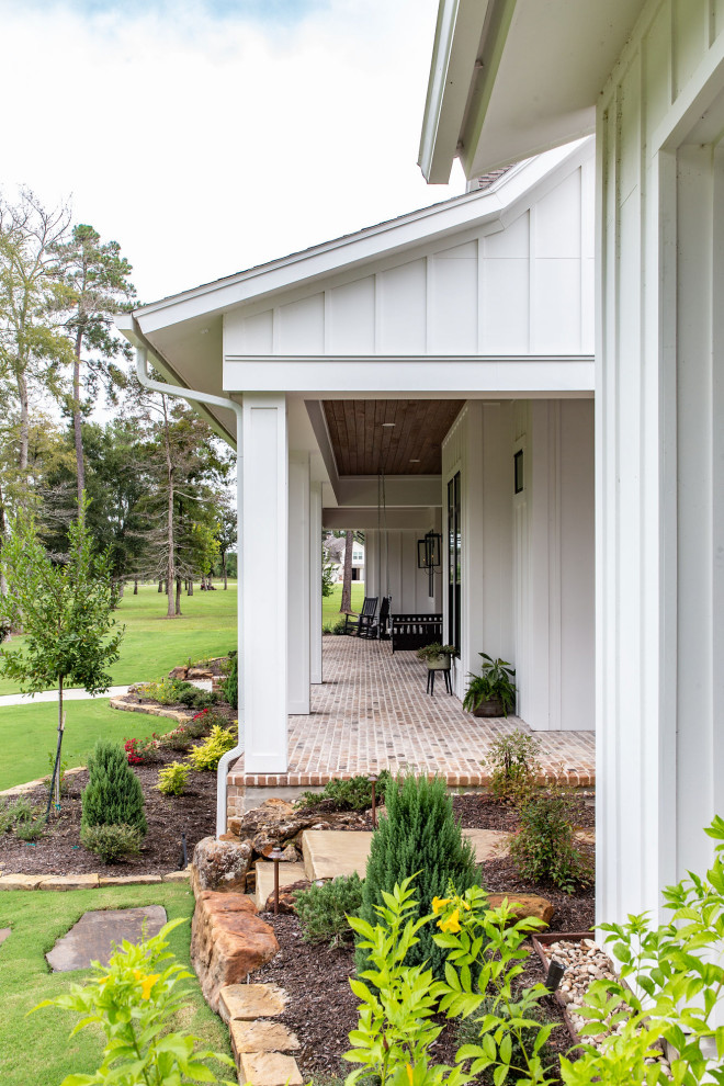Large country front yard verandah in Houston with with columns, brick pavers and a roof extension.