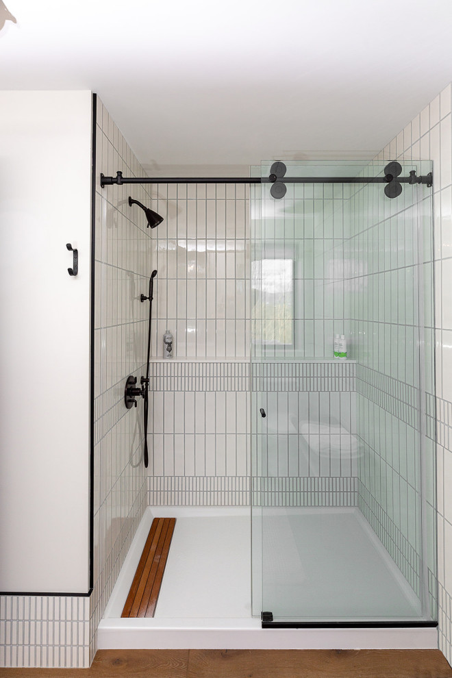This is an example of a medium sized contemporary shower room bathroom in Burlington with flat-panel cabinets, white cabinets, an alcove shower, a one-piece toilet, white tiles, ceramic tiles, white walls, medium hardwood flooring, an integrated sink, quartz worktops, a sliding door, white worktops, a single sink and a floating vanity unit.