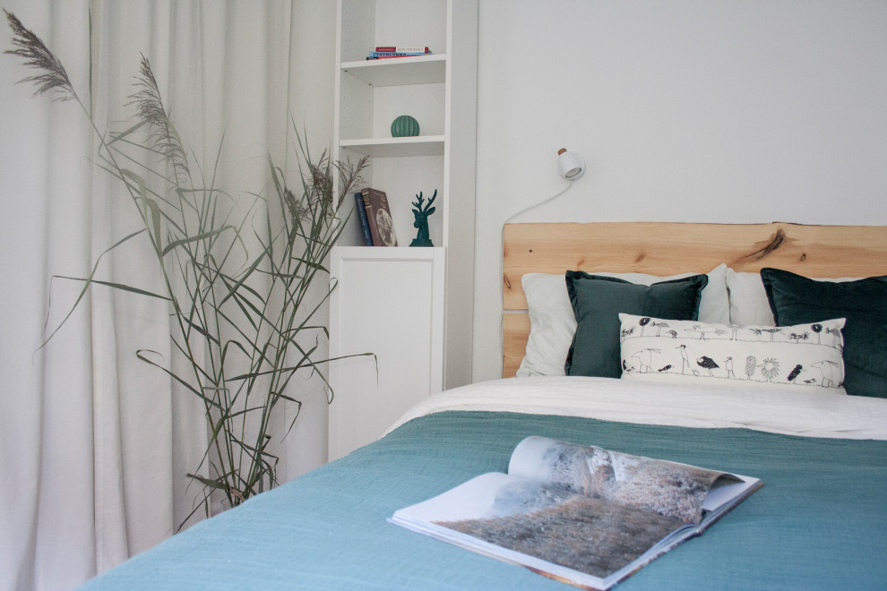 Cette photo montre une petite chambre blanche et bois scandinave avec un mur blanc, sol en stratifié et un sol marron.
