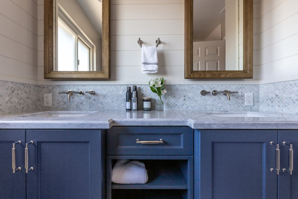 This is an example of a mid-sized transitional kids bathroom in San Francisco with shaker cabinets, blue cabinets, an undermount tub, a shower/bathtub combo, a one-piece toilet, gray tile, marble, grey walls, vinyl floors, an undermount sink, engineered quartz benchtops, grey floor, a shower curtain and white benchtops.
