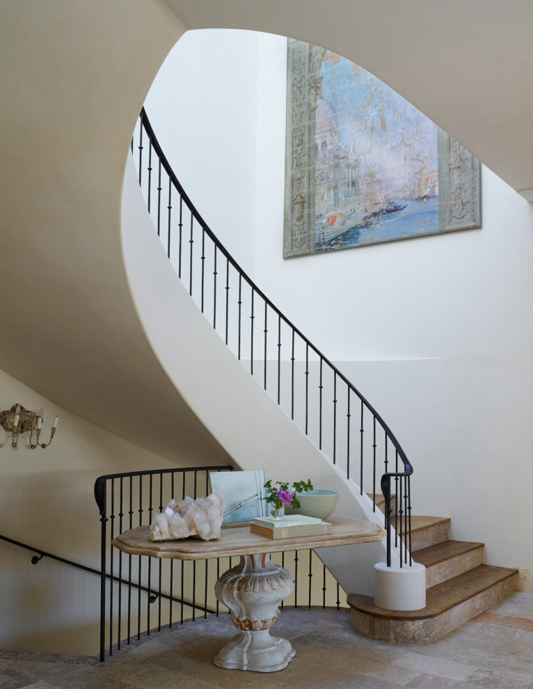 Example of a large tuscan wooden curved metal railing staircase design in Orange County with tile risers