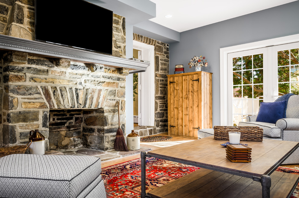 This is an example of a traditional family room in Philadelphia with grey walls, light hardwood floors, a standard fireplace and a stone fireplace surround.