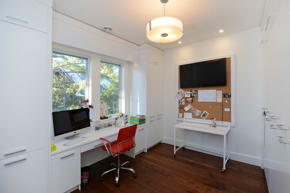 Modern home office in Other with white walls, medium hardwood floors, a built-in desk and brown floor.