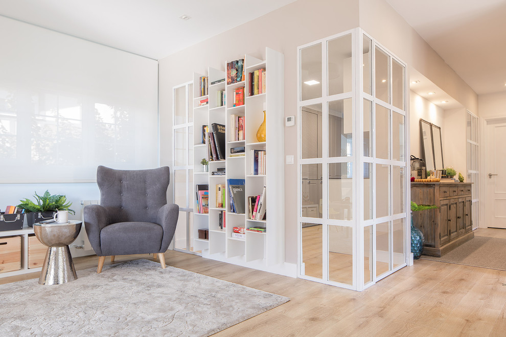 Inspiration for a mid-sized modern open concept living room in Bilbao with a library, grey walls, light hardwood floors, a freestanding tv and brown floor.