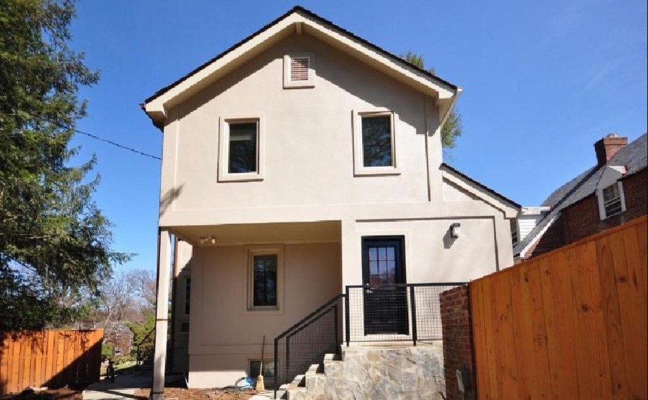 Large modern beige two-story stucco flat roof idea in DC Metro with a tile roof