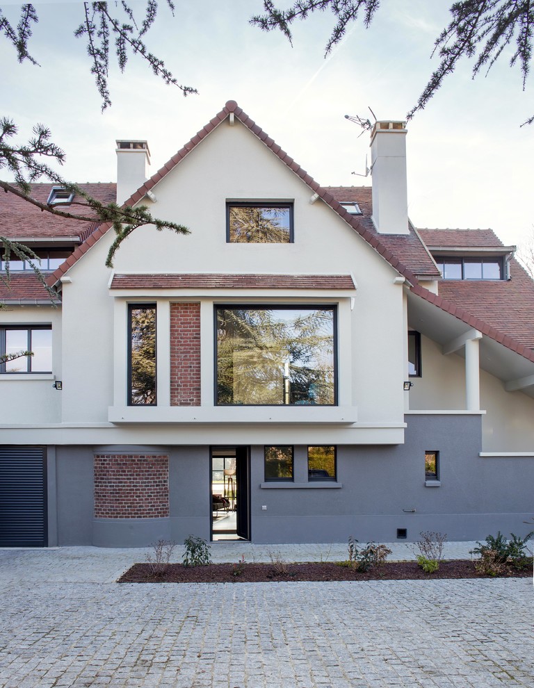This is an example of a large contemporary three-storey brick beige exterior in Paris with a gable roof.