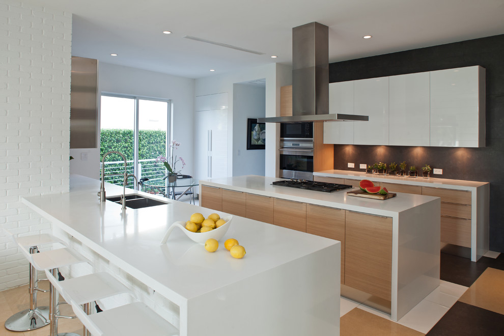 This is an example of a large contemporary galley eat-in kitchen in Miami with a double-bowl sink, flat-panel cabinets, light wood cabinets, stainless steel appliances, quartz benchtops, porcelain floors, with island and multi-coloured floor.