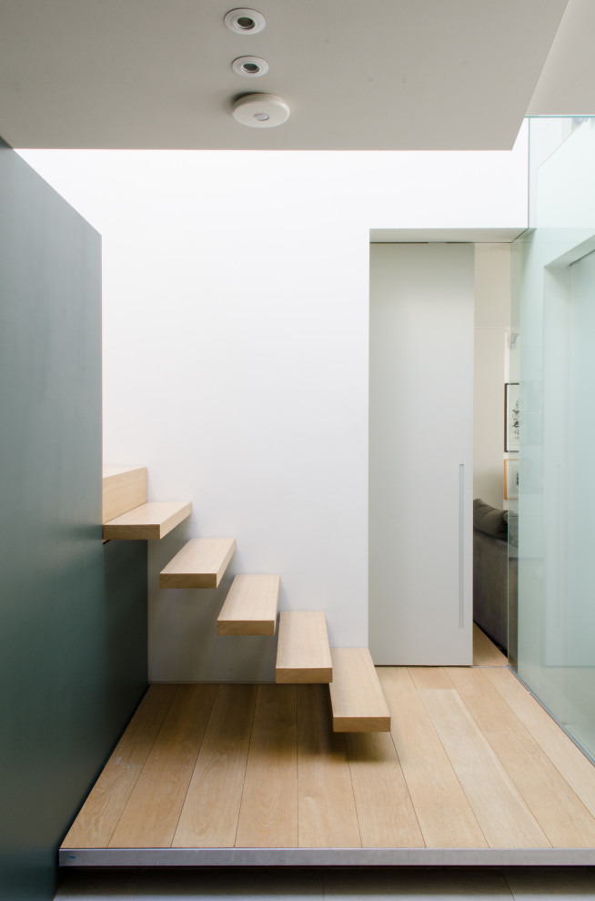 Diseño de escalera suspendida actual con escalones de madera y contrahuellas de madera