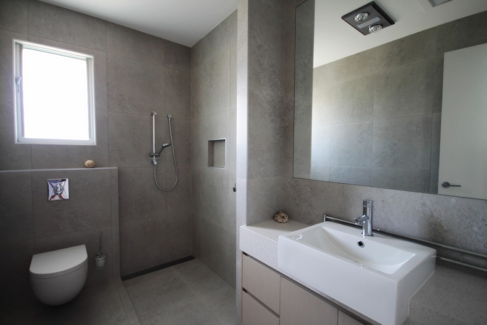 Photo of a mid-sized contemporary 3/4 bathroom in Sunshine Coast with flat-panel cabinets, light wood cabinets, an open shower, a wall-mount toilet, gray tile, porcelain tile, grey walls, porcelain floors, a vessel sink and engineered quartz benchtops.