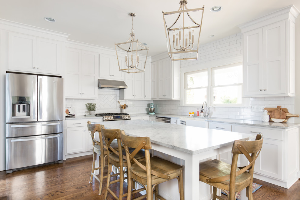 Design ideas for a traditional l-shaped eat-in kitchen in Richmond with a farmhouse sink, shaker cabinets, white cabinets, marble benchtops, white splashback, subway tile splashback, stainless steel appliances, dark hardwood floors, with island and brown floor.