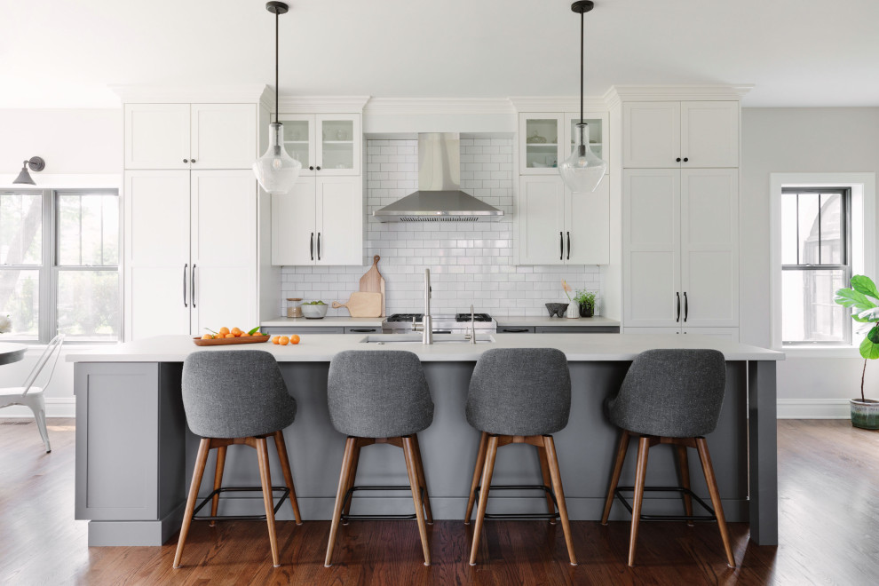 This is an example of a transitional single-wall eat-in kitchen in Chicago with an undermount sink, shaker cabinets, white cabinets, concrete benchtops, white splashback, subway tile splashback, stainless steel appliances, medium hardwood floors, with island and white benchtop.