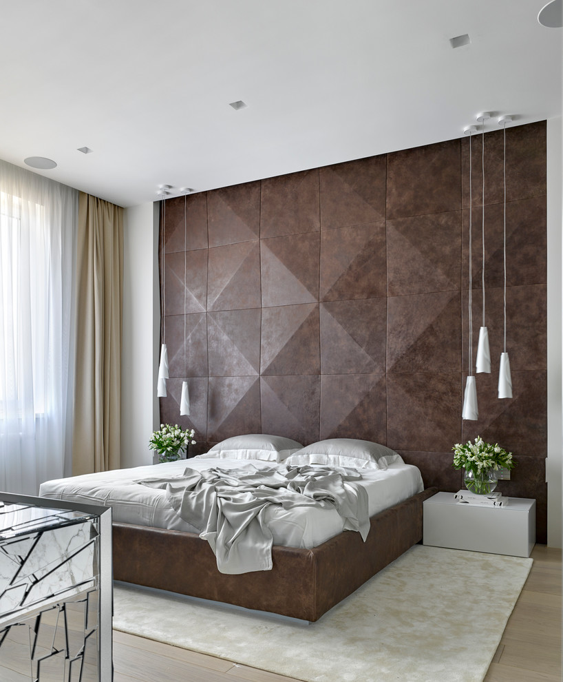 This is an example of a contemporary master bedroom in Moscow with brown walls and light hardwood floors.