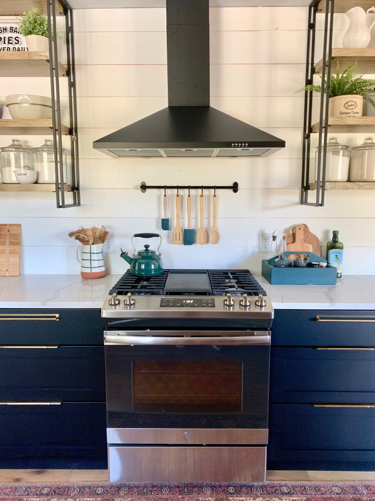 This is an example of a large country galley separate kitchen in Other with an undermount sink, shaker cabinets, black cabinets, quartzite benchtops, white splashback, shiplap splashback, stainless steel appliances, light hardwood floors, a peninsula, beige floor and white benchtop.